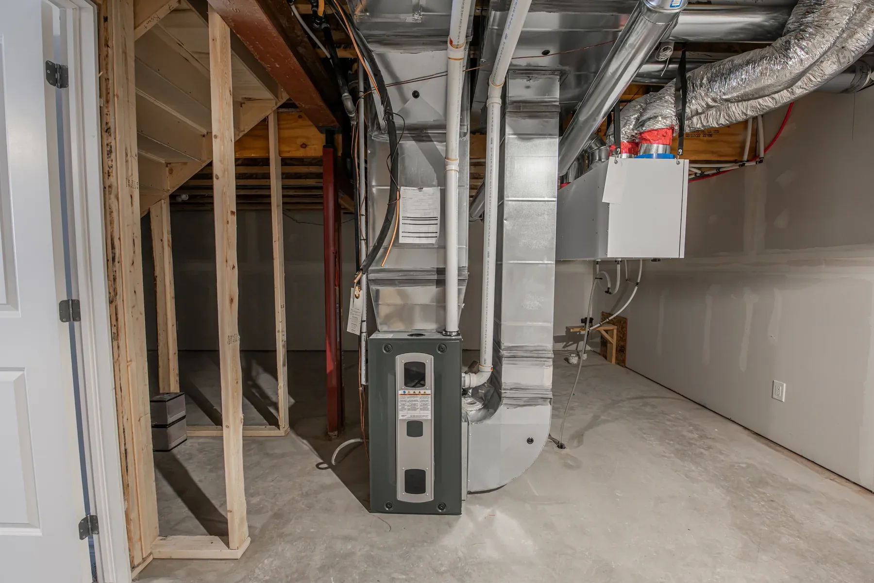 Indoor furnace and air handler connected to metal supply ductwork in an unfinished utility room